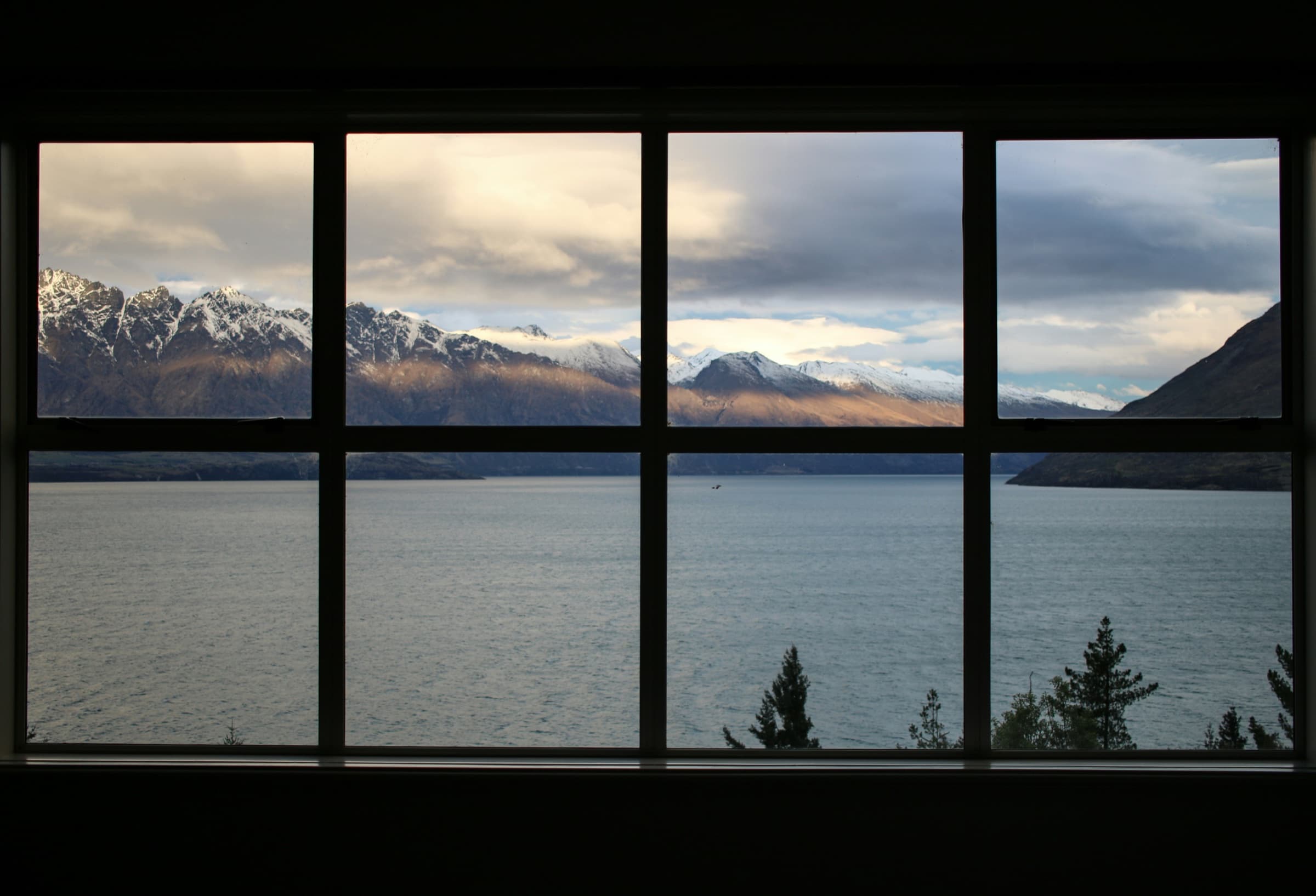 Large multi-panel window overlooking mountains and water